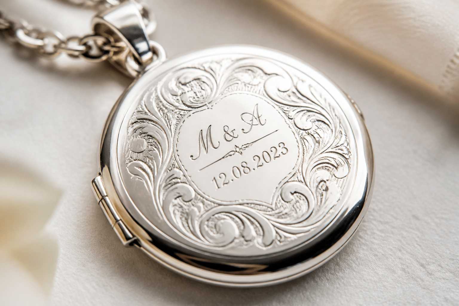 Edle Hochzeitsgeschenke personalisiert: Kein Kitsch, nur Stil 4 Edle Hochzeitsgeschenke personalisiert Nahaufnahme einer präzisen und eleganten Lasergravur von Initialen und einem Datum auf einem silbernen Medaillon, das die Gravur-Qualität für personalisierte Hochzeitsgeschenke hervorhebt.